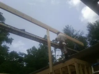 Carpenter setting a ridge beam over a new addition frame — Ice Dam Removal by Roofing Brothers in Hobgood