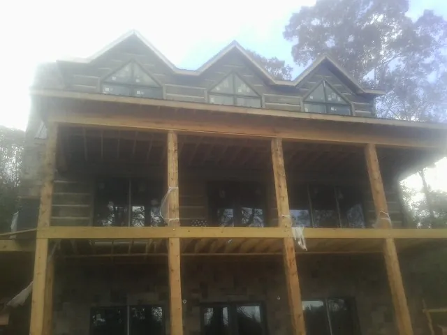 Dormers and porch framing on a large log home under construction — Roof Coating work by our crew in Hobgood