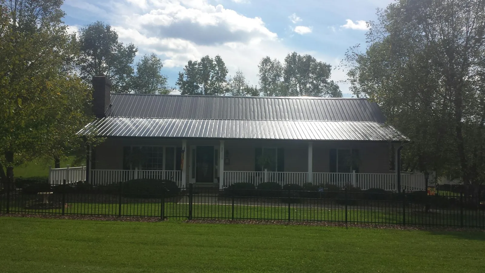 Gray metal roof on a brick ranch with a full width front porch — Gutter Guard Installation work by our crew in Hobgood