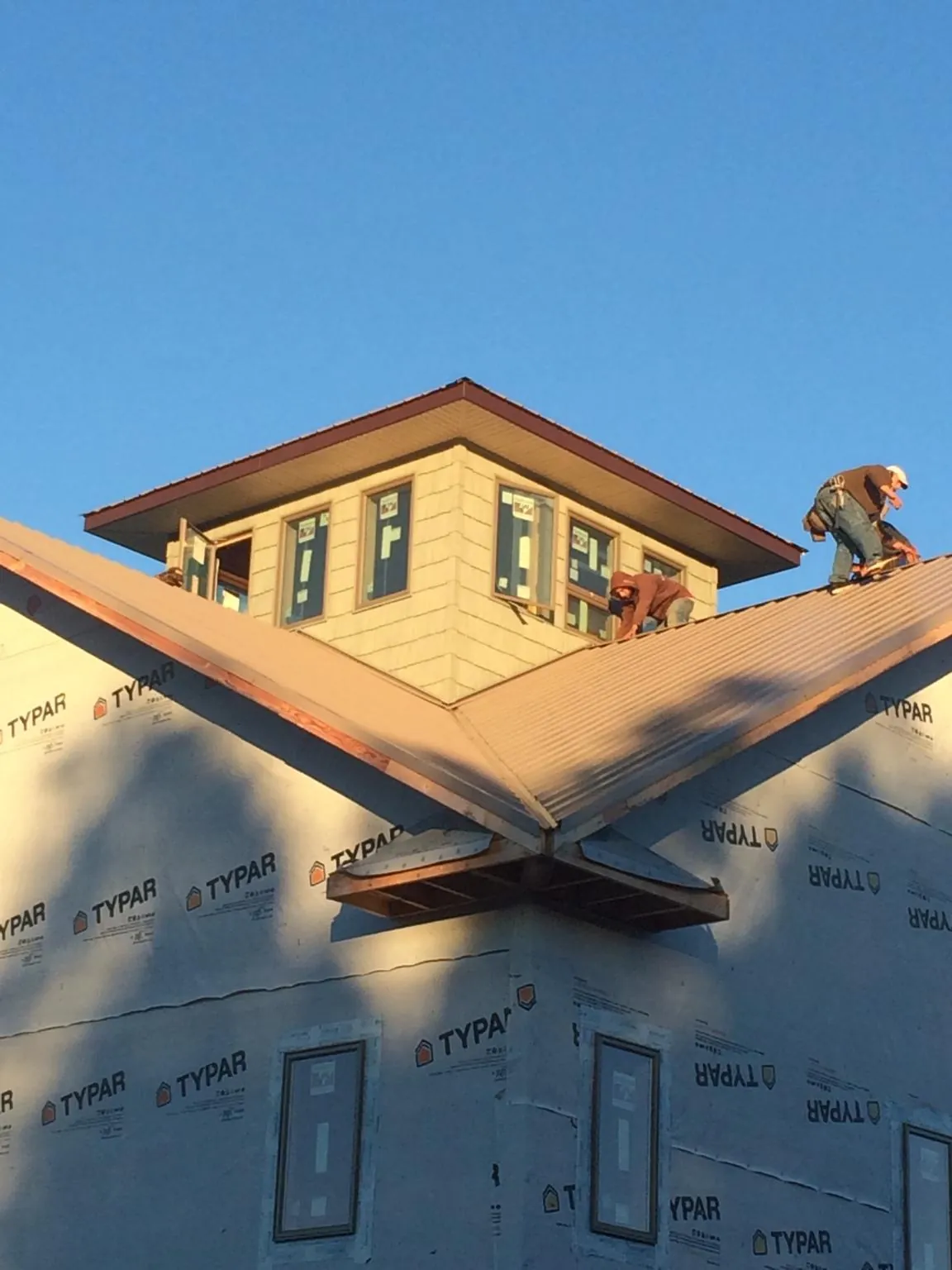 Roofers working around a rooftop cupola on a new metal roof at sunset — Roof Waterproofing in Hobgood by Roofing Brothers